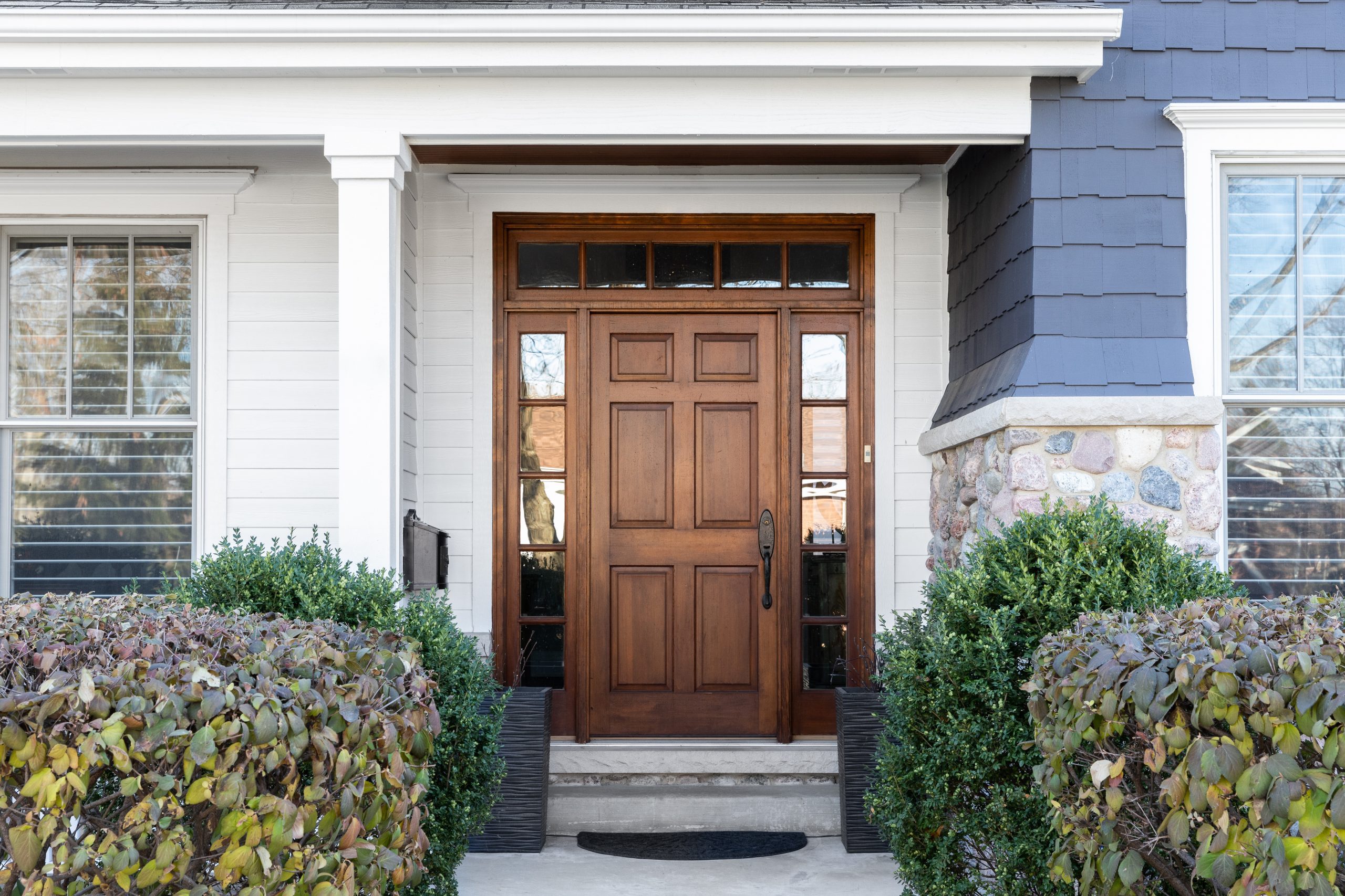 A wooden front door, surrounded by windows, with white, blue, an